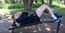 Träning på situpsbänk i utemiljö där kvinna utför situps.