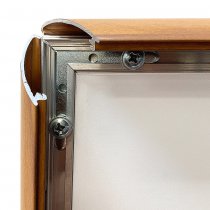 Närbild på öppnad snäppram med träimitation, aluminiumprofil och skruvfästen